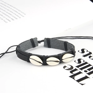 Detail of bohemian shell leather bracelet with adjustable cord on book background