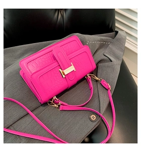 Macro detail of magenta crocodile embossed leather with signature gold H-clasp