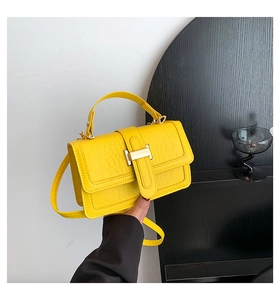 Detail of yellow crocodile texture leather bag with iconic golden H metal clasp