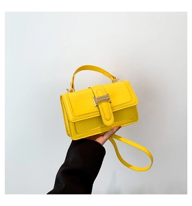 Detail view of yellow faux crocodile leather handbag with elegant gold metal buckle