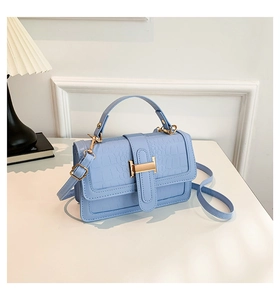 Detail of light blue faux crocodile leather bag with gold H-shaped clasp and pleated lamp
