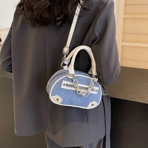 Sac demi-lune en denim bleu avec chaînes argentées et garniture en cuir sur modèle