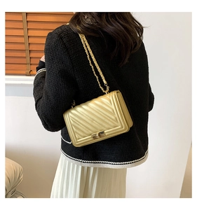 Golden chevron quilted bag with chain strap shown on a model in a stylish interior