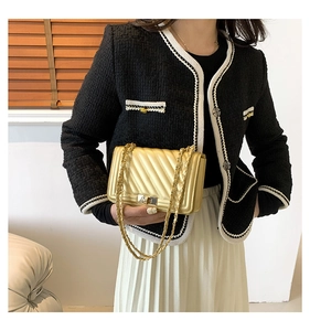 Detail of elegant gold quilted chain bag and black tweed jacket with woven texture