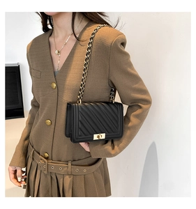 Detail of black quilted leather shoulder bag featuring golden chain and vintage square lock