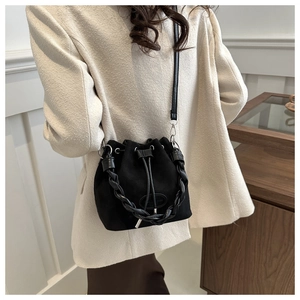 Close-up of black matte bucket bag featuring a woven top handle and drawstring closure