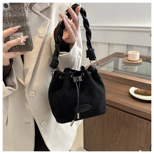 Détail du sac seau noir en daim avec poignée tressée et fermeture par cordon de serrage chic