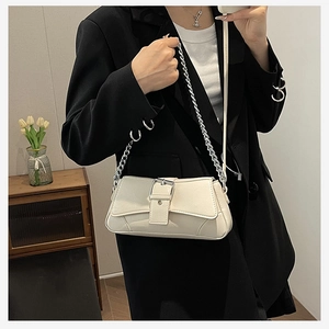 Close-up of a stylish cream PU leather underarm bag with a bold silver chain and buckle