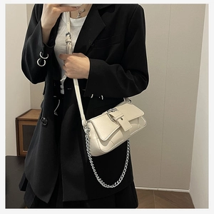 Chic beige leather crossbody bag with chain strap and metal buckle, shown on model