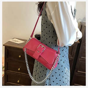 Close-up of magenta faux leather shoulder bag with bold silver metal buckle and chain strap