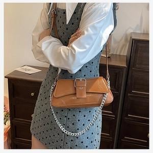 Close-up of caramel brown crossbody bag with silver chain and metal buckle detail