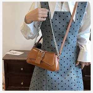 Detail of vintage brown PU leather crossbody bag with silver chain strap on a model