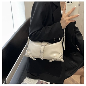 Detail of off-white PU leather shoulder bag with silver buckle straps worn by a model
