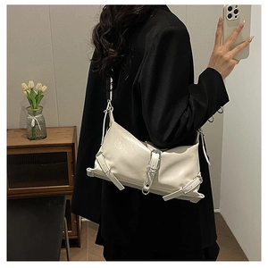 Detailed view of off-white glossy patent leather shoulder bag with decorative metal buckles