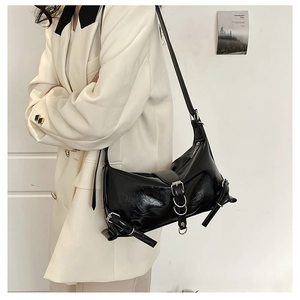 Detail of black glossy hobo bag with silver buckles showing shoulder carry on model