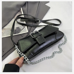 Detail of black pleated faux leather bag with silver buckle and metallic chain strap