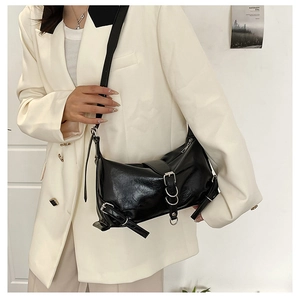 Detail of black glossy leather underarm bag featuring silver metal buckle and ring accents