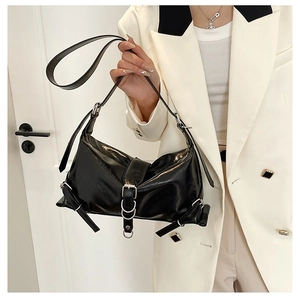 Detail of black motorcycle shoulder bag with silver buckles and glossy leather texture