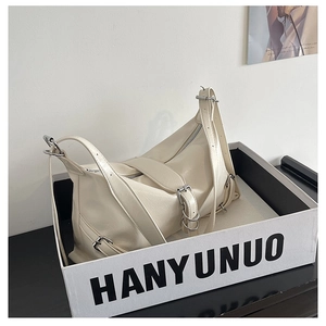 Detail of cream white crinkled patent leather shoulder bag with silver buckle accents