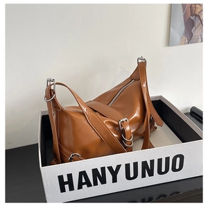 Detailed view of brown glossy moon-shaped bag in a white presentation box