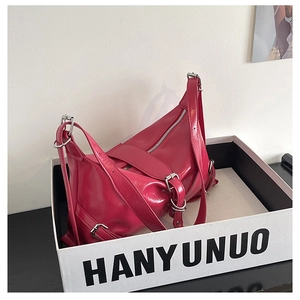Detail of fuchsia PU leather shoulder bag featuring silver metal zippers and buckles