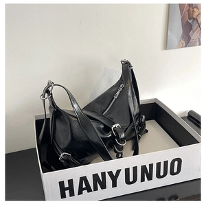 Detail of glossy black shoulder bag with silver buckles and metal hardware accents