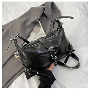 Detailed view of black motor-style shoulder bag with silver buckles and leather texture