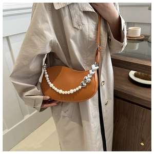Detail of orange-brown crescent saddle bag with pearl and silver heart shoulder strap