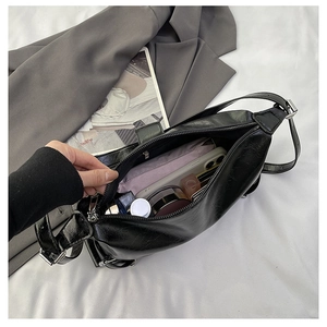 Close-up of black crackle leather shoulder bag showing spacious interior with daily items