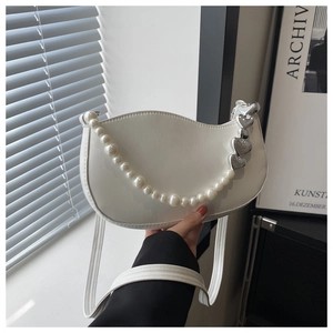 Detail of white crescent bag showing pearl chain and silver heart-shaped metal accents
