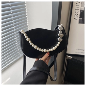 Detail of black matte leather crescent bag with white pearls and silver heart charms