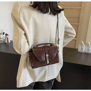 Détail du sac carré vintage en cuir huilé marron avec fermoir métallique sur le mannequin