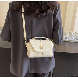 Détail d'un sac à main vintage beige en cuir avec boucle dorée ronde sur un mannequin