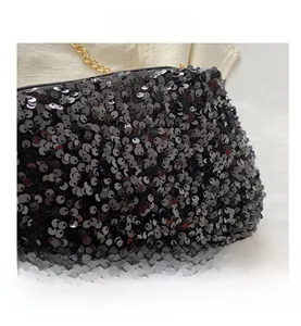 Close-up of black sequined crossbody bag with gold metal chain strap and zip detail