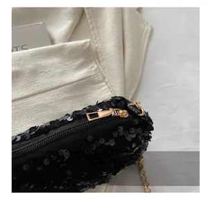 Detailed close-up of the smooth golden zipper and black sequins on a fashion chain bag