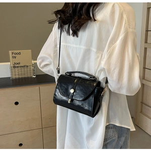 Modèle portant un sac bandoulière vintage en cuir huilé noir au design élégant