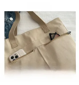 Vue détaillée du sac cabas en toile beige avec poches extérieures et design décontracté