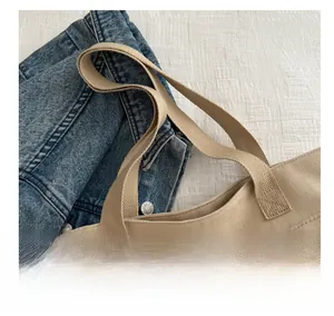 Détail du sac cabas en toile beige montrant les coutures et la fermeture éclair