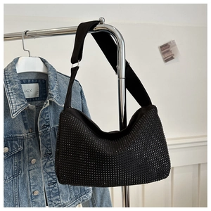 Close-up of black rhinestone tote bag with wide canvas strap hanging on an indoor rack
