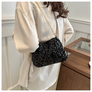 Detailed macro view of black sequin underarm bag with elegant gold metal chain strap