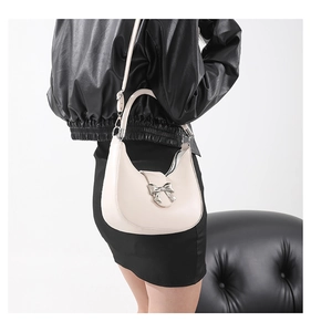 Détail du sac hobo crème avec nœud argenté porté par un mannequin en gros plan