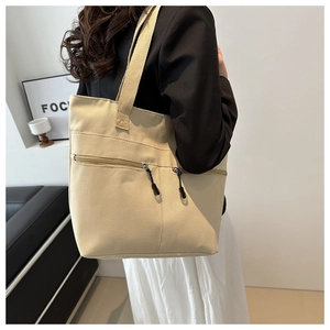 Vue détaillée du sac fourre-tout en toile beige avec deux poches zippées sur un mannequin