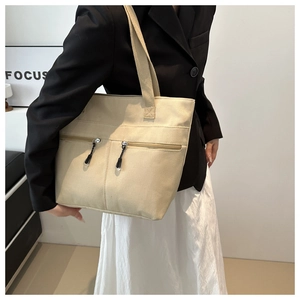 Détail du sac cabas en toile beige avec deux poches zippées sur un mannequin mode