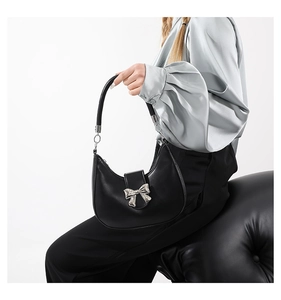 Détail d'un sac hobo noir avec un nœud argenté et une texture en cuir de qualité