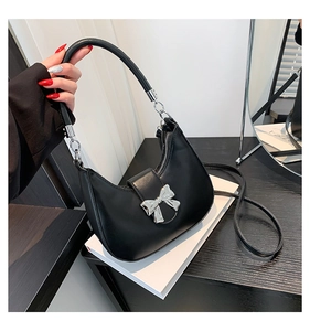 Détail du sac demi-lune noir avec un nœud métallique argenté et une texture en cuir PU