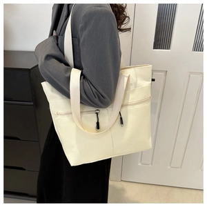 Détail du cabas en toile crème avec larges bandoulières et doubles poches zippées