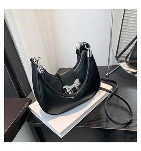 Détail d'un sac demi-lune en cuir PU noir avec boucle noeud en métal argenté et bandoulière