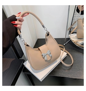 Détail du sac demi-lune beige avec un nœud en métal argenté et une texture en similicuir lisse