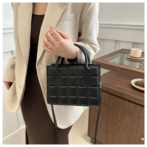 Classic black quilted square handbag with dual handles shown in a lifestyle setting