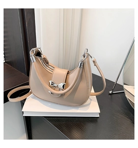 Détail du sac demi-lune beige avec boucle de nœud argentée et cuir mat de haute qualité